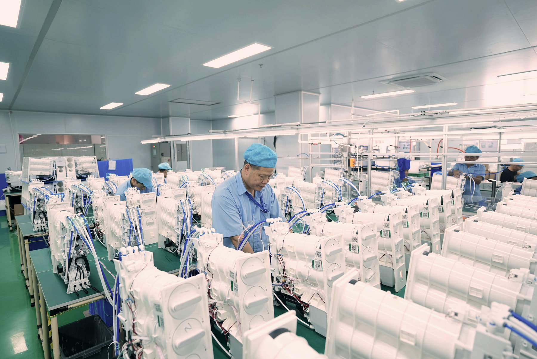 Production teams assembling countertop water purification appliances across coordinated workstations.