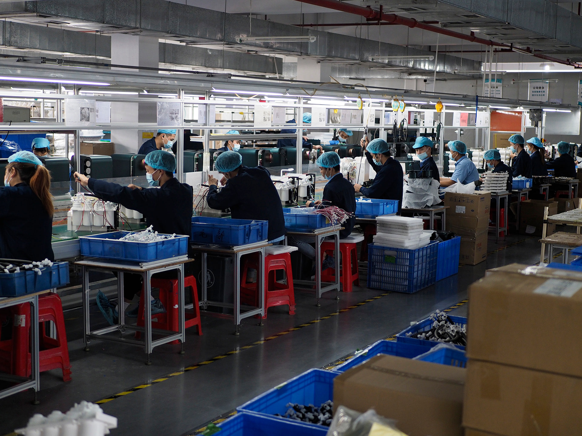 Masked production team working across a controlled assembly workshop.