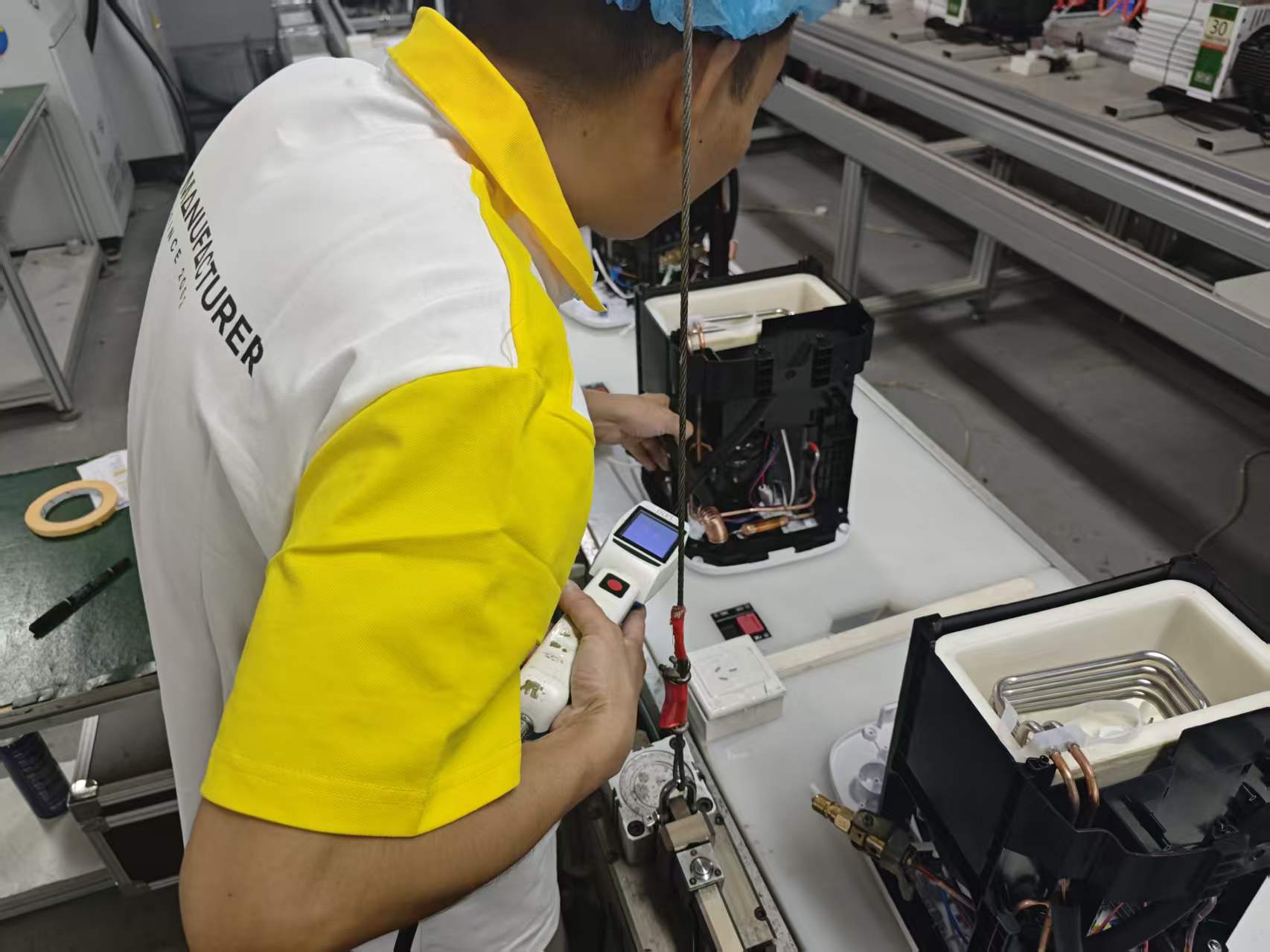 Operator checking refrigeration pipe connections with a handheld leak detector.