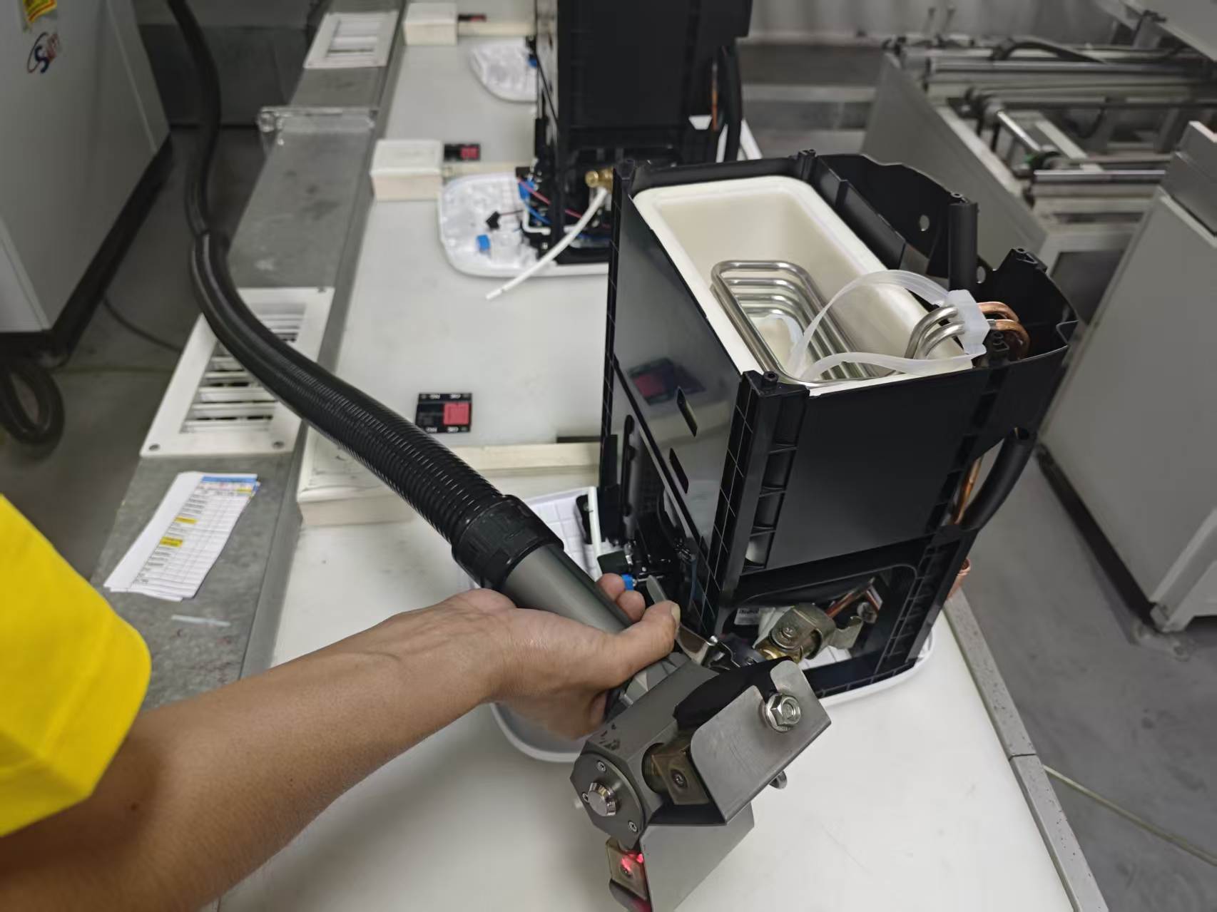 Operator using a refrigerant charging tool on an exposed chilled-water assembly.