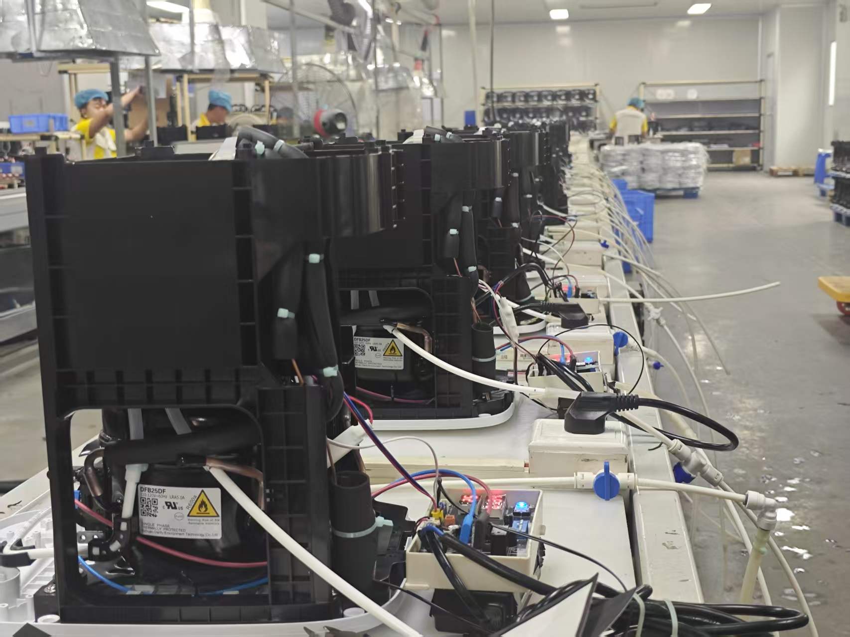Rows of refrigeration assemblies connected to water tubing and electrical controls during aging tests.