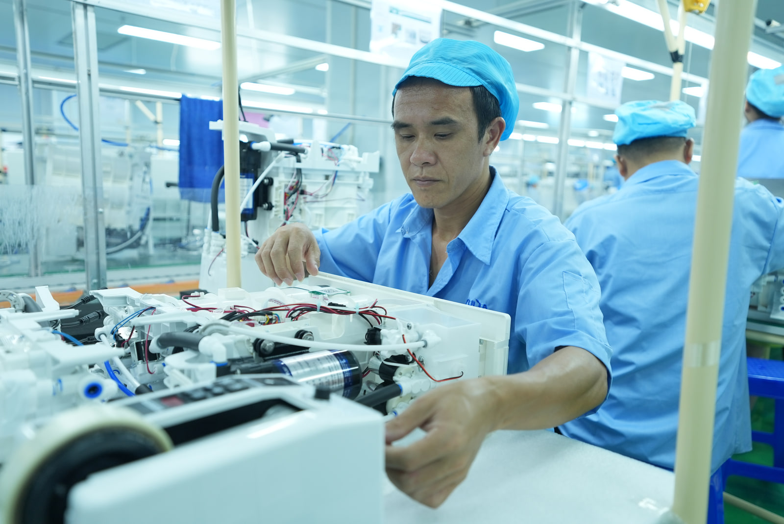 A factory technician assembling the internal components of a water appliance.