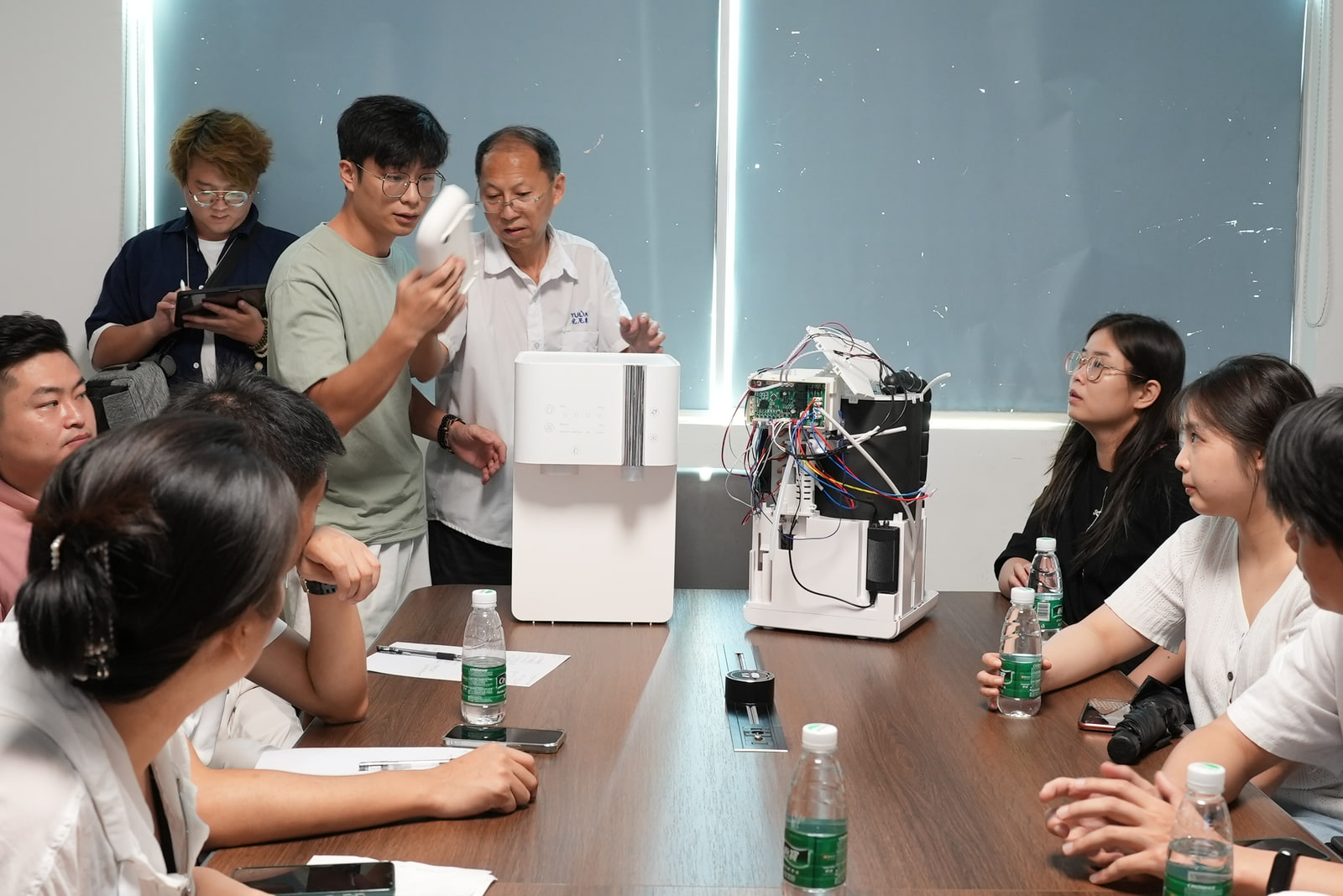 A product team reviewing finished and opened water-appliance prototypes.