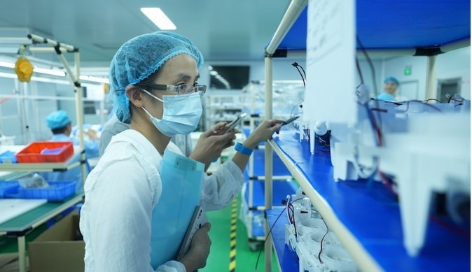 A production inspector checking water-appliance wiring and assembly on the line.