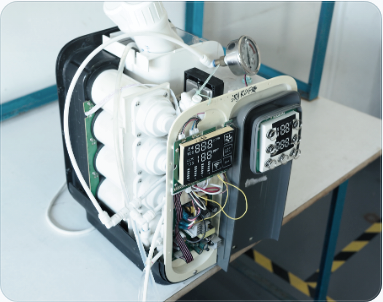 An opened appliance with visible water paths, pressure gauge, and live test displays.